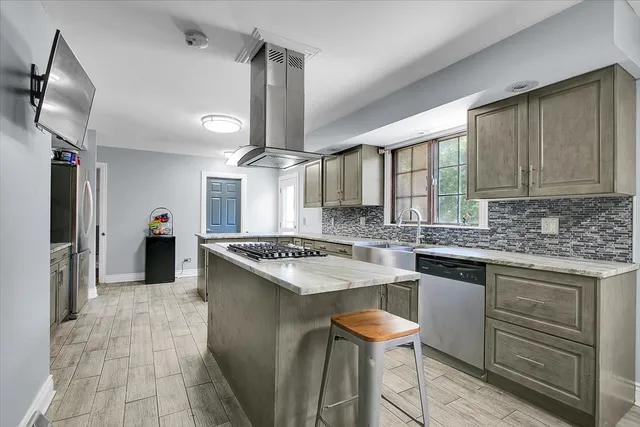 a kitchen with a stove a sink a refrigerator and chairs