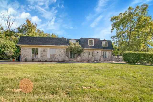 a front view of house with yard and trees in the background