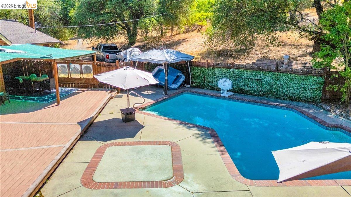 8733 Fraguero Road Sonora, CA 95370 - Photo 60 of 73 Freeform swimming pool with brick coping surrounded by concrete decking, featuring an integrated spa area