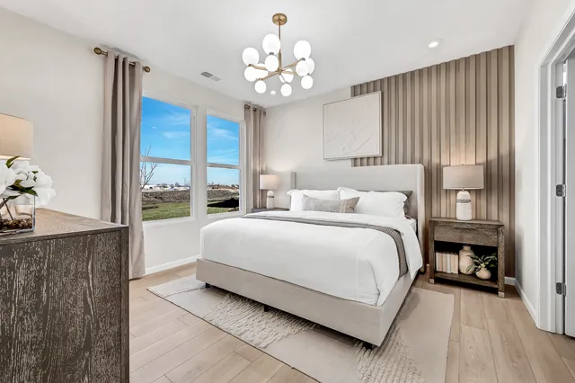 a bedroom with a large bed chandelier and a window