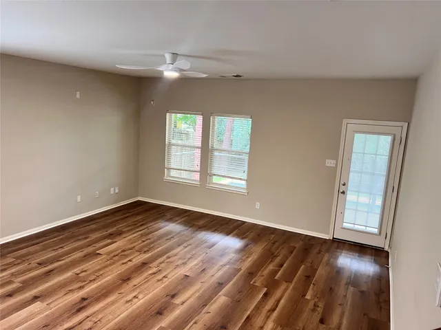 a view of a living room with kitchen appliances wooden floor and windows