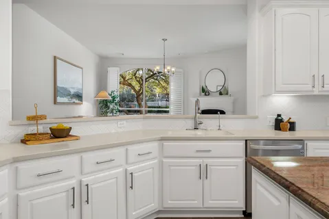 a kitchen with white cabinets and sink
