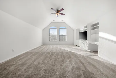 an empty room with windows and ceiling fan