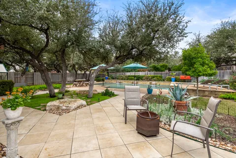 a view of a patio with a dining table and chairs potted plants and a large tree