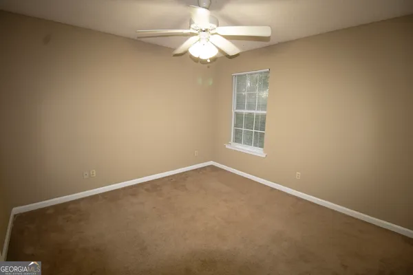 an empty room with a window and a fan