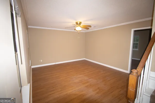 an empty room with wooden floor and fan
