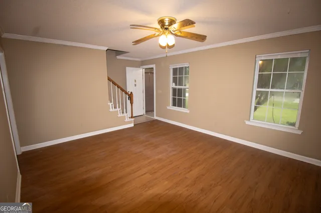a view of an empty room with a window and wooden floor