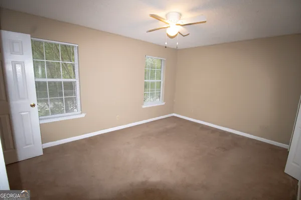 an empty room with a window and a fan