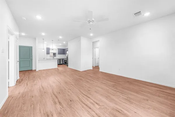 a view of an empty room with window and wooden floor