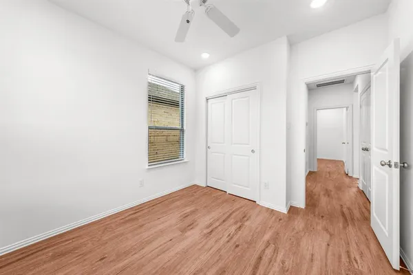 an empty room with wooden floor chandelier fan and windows