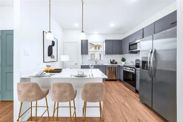 a kitchen with stainless steel appliances kitchen island granite countertop a table chairs refrigerator and microwave