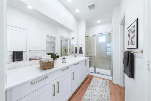 a large bathroom with a double vanity sink a large mirror a shower and vanity