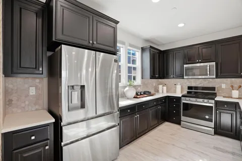 a kitchen with granite countertop a refrigerator stove and sink