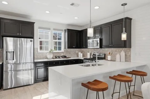 a kitchen with stainless steel appliances a sink a stove a refrigerator and cabinets