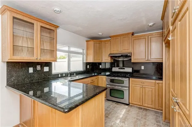 a kitchen with stainless steel appliances granite countertop a stove a sink and a microwave