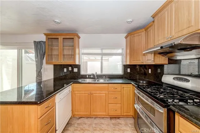a kitchen with granite countertop a sink a counter space appliances and cabinets