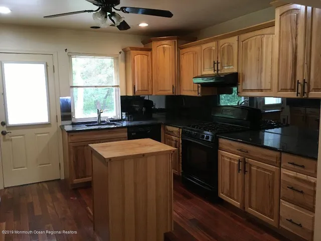 a kitchen with kitchen island granite countertop a sink appliances cabinets and a counter top space