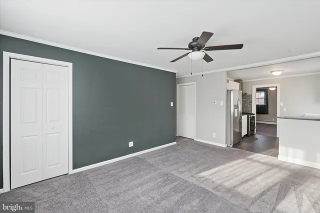 a view of a livingroom with a ceiling fan & kitchen space