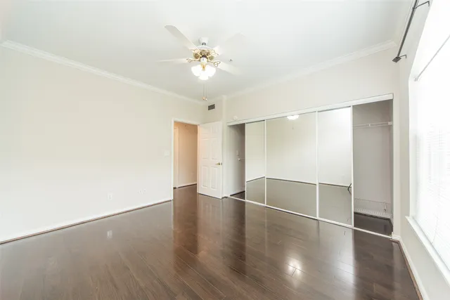 an empty room with wooden floor and chandelier fan