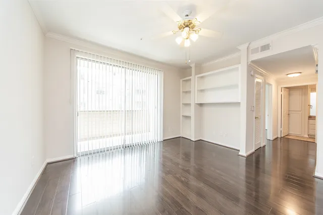 a view of an empty room with a window and wooden floor