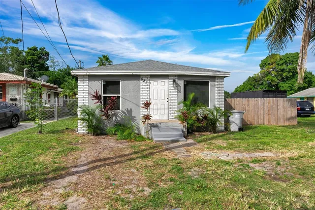 a view of a house with a small yard and a large tree