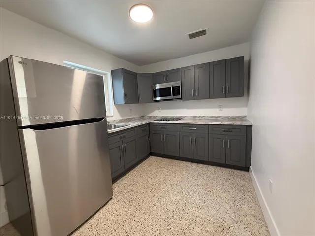 a kitchen with stainless steel appliances granite countertop a refrigerator a sink and a stove