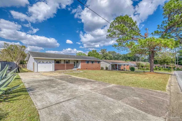 a front view of house with yard and trees in the background