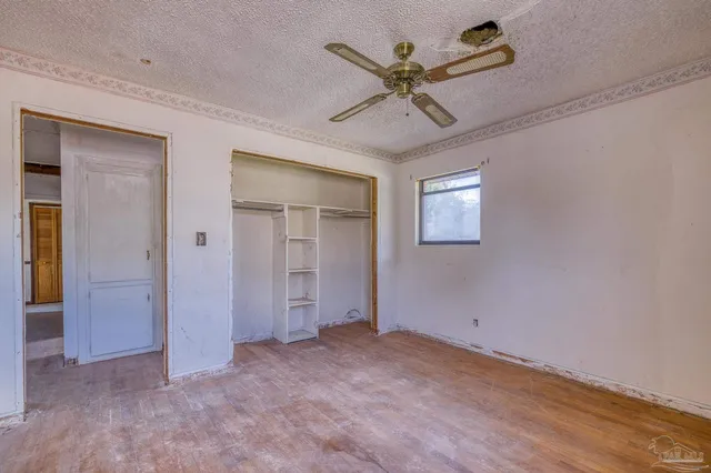 an empty room with a window and ceiling fan