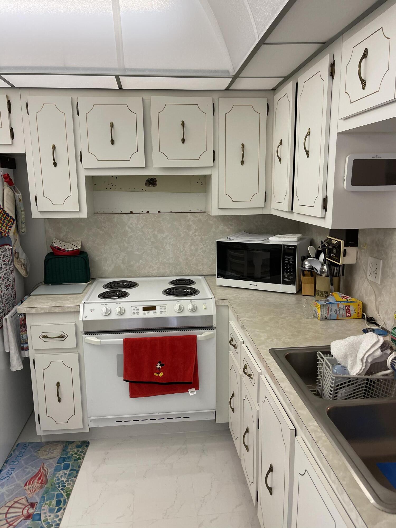4291 Northwest 9th Avenue, Unit 104 Deerfield Beach, FL 33064 - Photo 8 of 11 a kitchen with white cabinets and white appliances
