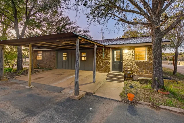 a view of a house with a large tree and wooden fence