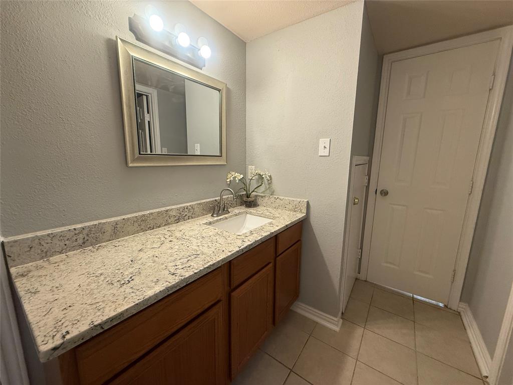 5981 Arapaho Road, Unit 1503 Dallas, TX 75248 - Photo 11 of 14 a bathroom with a granite countertop sink and a mirror