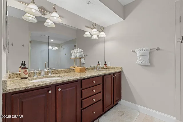 a bathroom with a granite countertop double vanity sink and a mirror