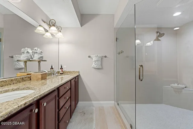 a bathroom with a granite countertop sink a large mirror and shower