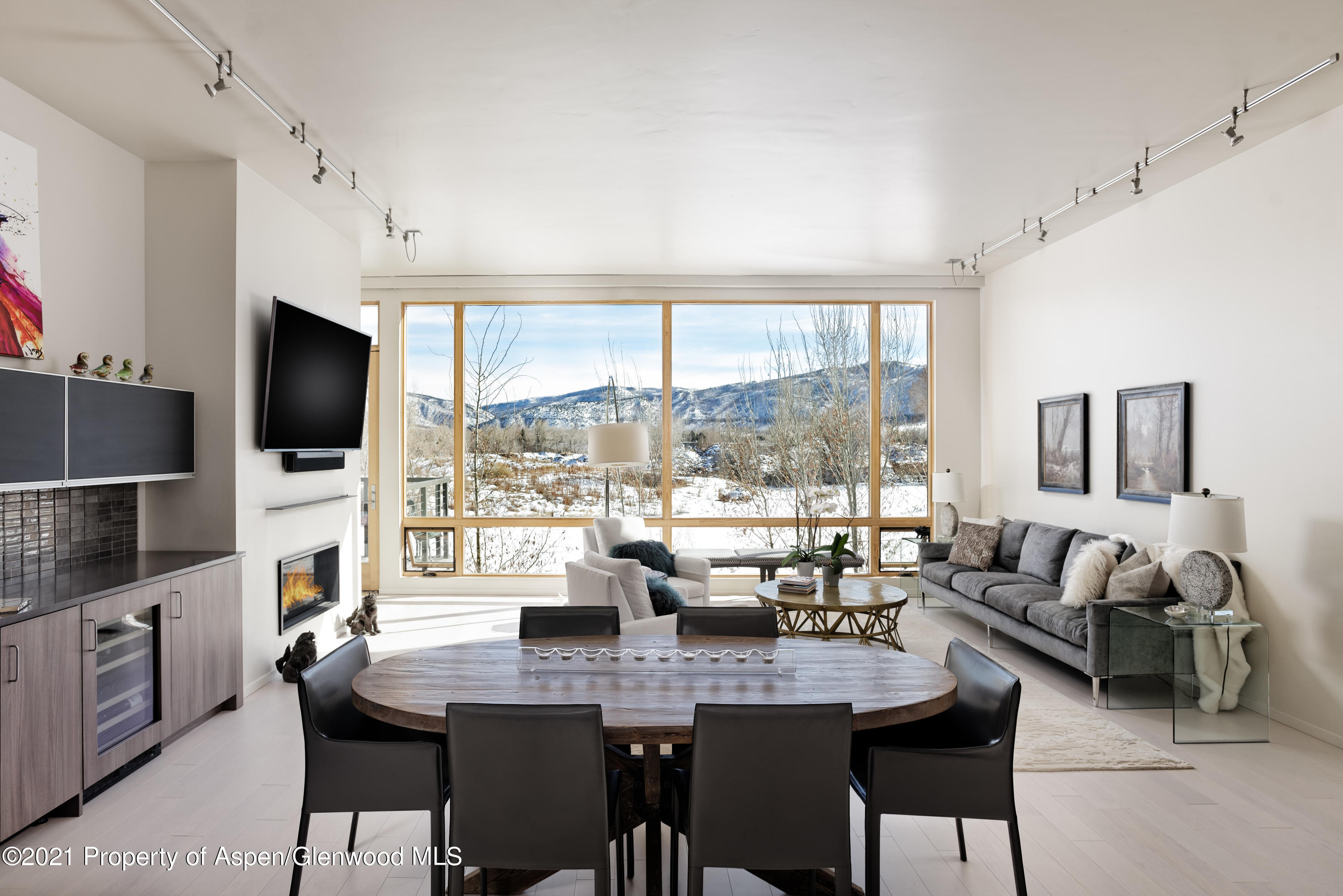 a dining room with furniture a large window and a flat screen tv