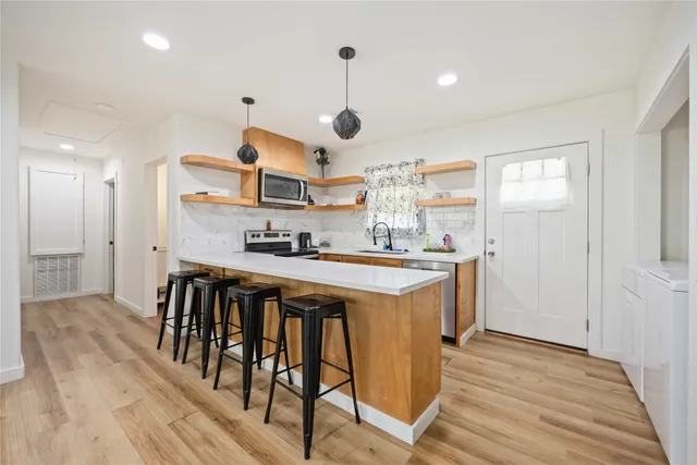 a kitchen with kitchen island a wooden floor and white appliances