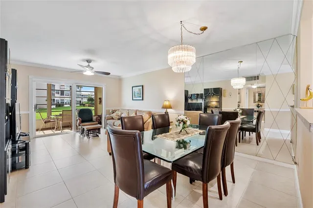 a view of a dining room and livingroom with furniture wooden floor a rug a painting and a chandelier