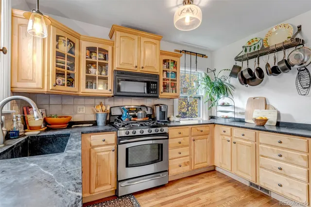 a kitchen with a sink and a stove with wooden floor