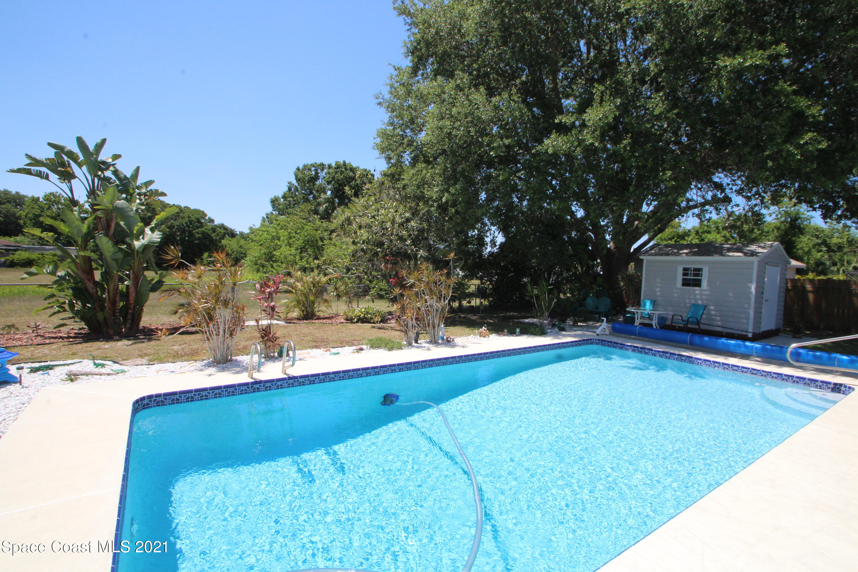 1398 Creel Road Northeast Palm Bay, FL 32905 - Photo 25 of 37 a backyard of a house with table and chairs and a large tree
