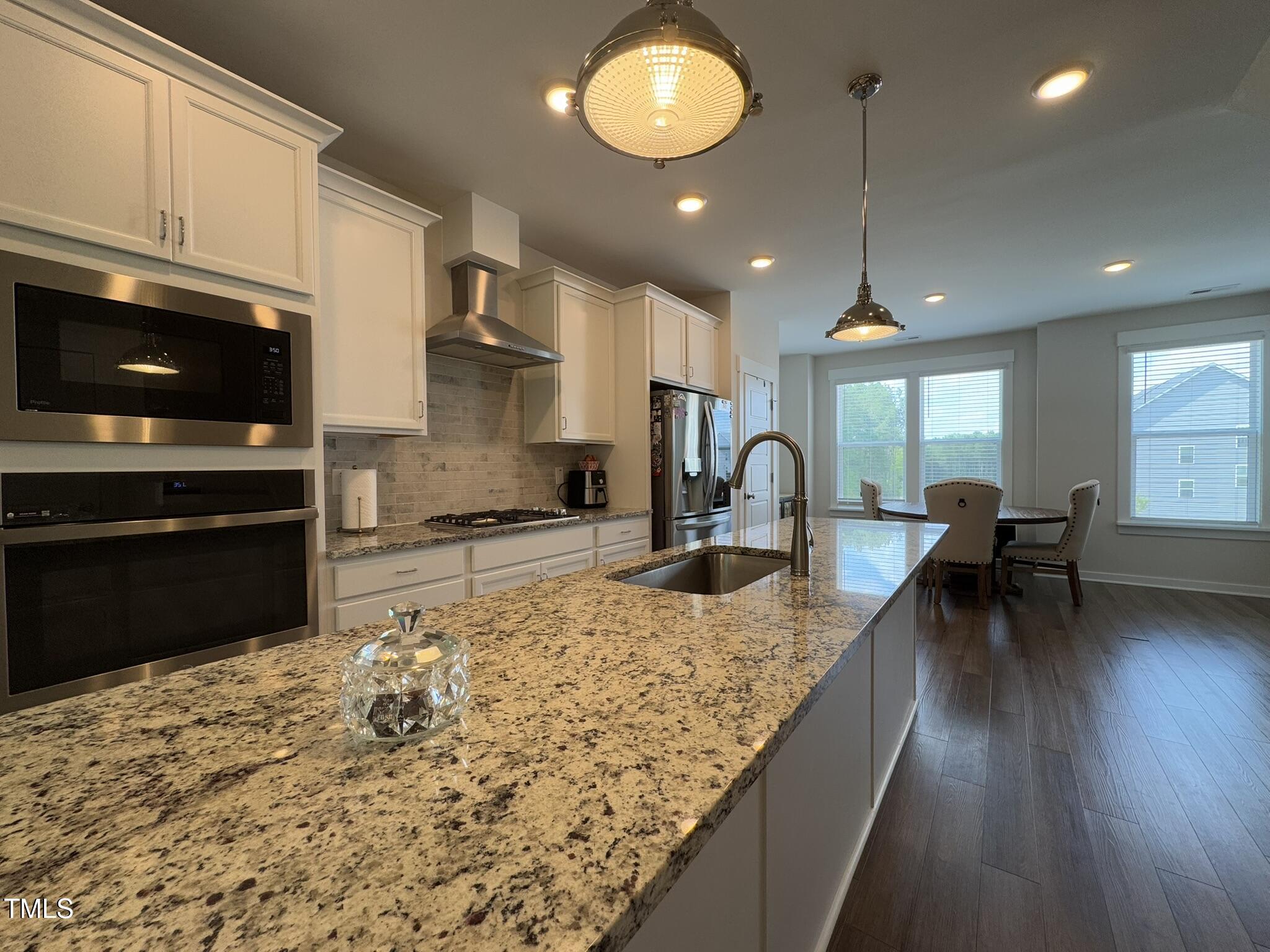1244 Corkery Ridge Court Cary, NC 27519 - Photo 6 of 37 a kitchen with kitchen island granite countertop a stove a sink a dining table and chairs with wooden floor
