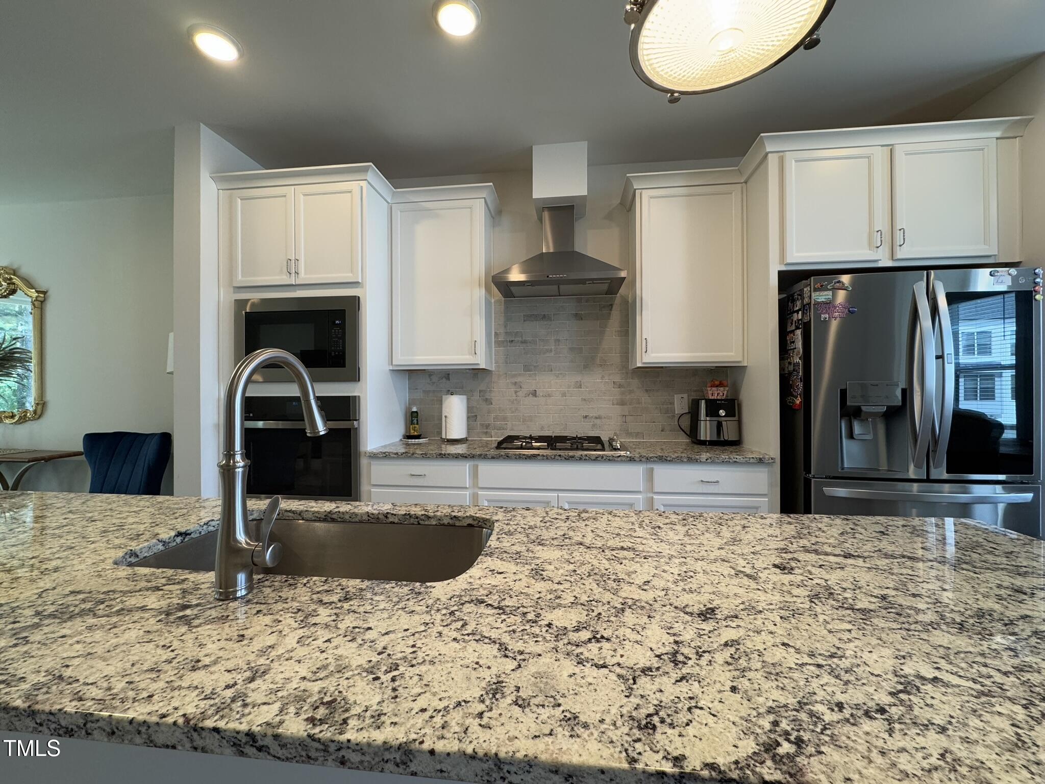 1244 Corkery Ridge Court Cary, NC 27519 - Photo 7 of 37 a kitchen with kitchen island granite countertop a stove a sink and a refrigerator