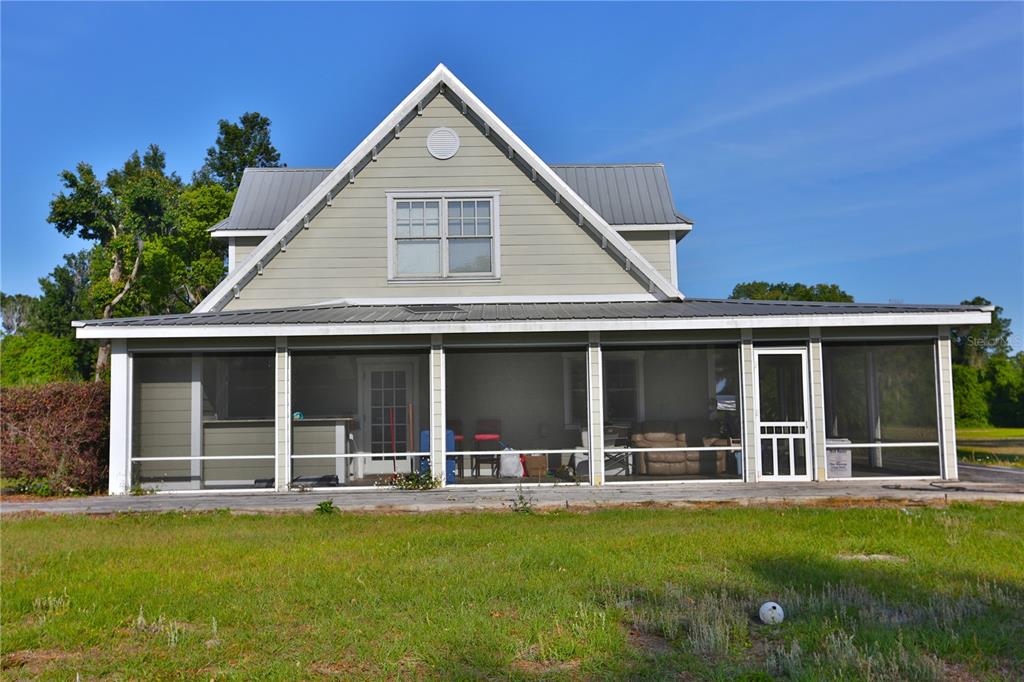 12115 Southeast Sunset Harbor Road Weirsdale, FL 32195 - Photo 11 of 35 a view of a white house with a large windows and a yard with palm trees