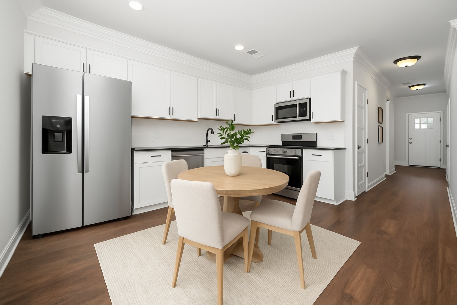 a kitchen with stainless steel appliances a dining table chairs refrigerator and microwave