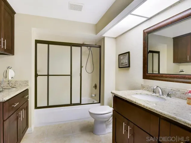 a bathroom with a granite countertop sink toilet and shower