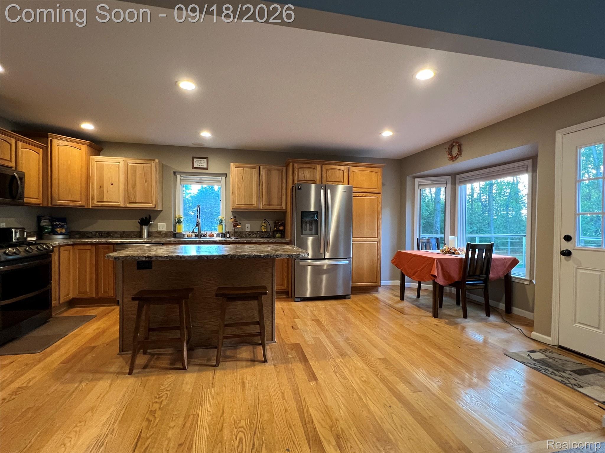 7070 Elms Road Swartz Creek, MI 48473 - Photo 7 of 27 Kitchen featuring wood-finish flooring, recessed lighting, and a breakfast bar with a stone countertop
