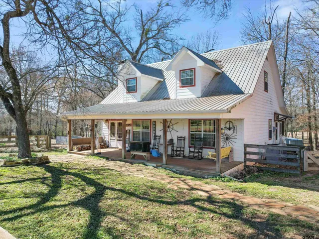 a view of a white house with a yard and sitting area