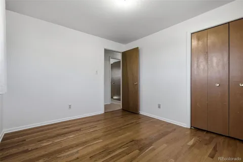 a view of an empty room with wooden floor and closet