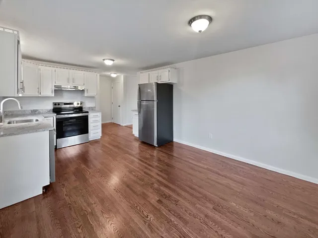 a kitchen with stainless steel appliances wooden floors and white cabinets