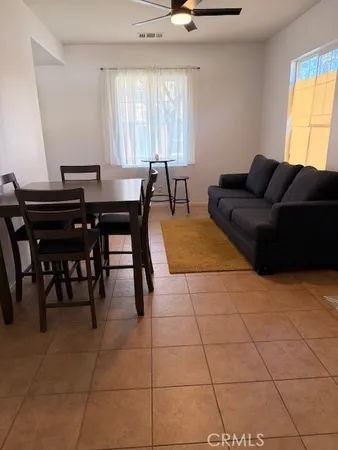 a living room with couches a dining table and a piano table with wooden floor