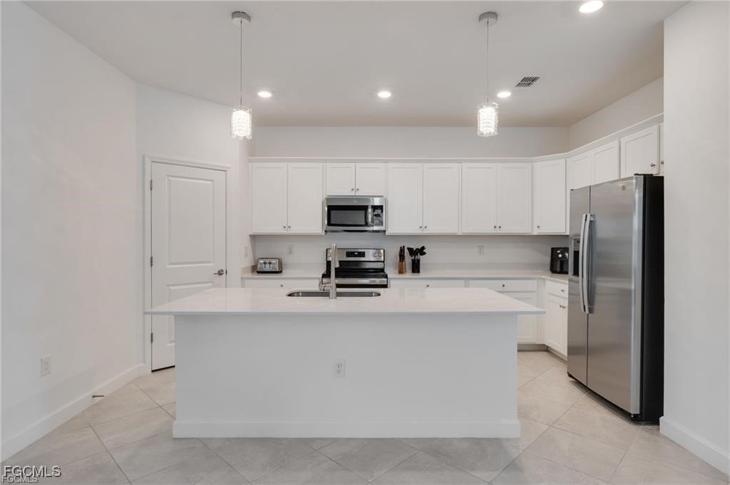 9146 Leatherwood Loop Lehigh Acres, FL 33936 - Photo 9 of 43 a kitchen with stainless steel appliances a refrigerator sink and microwave