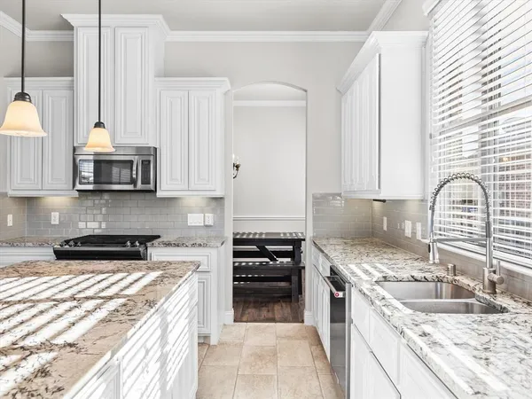 a kitchen with granite countertop a sink a stove and cabinets
